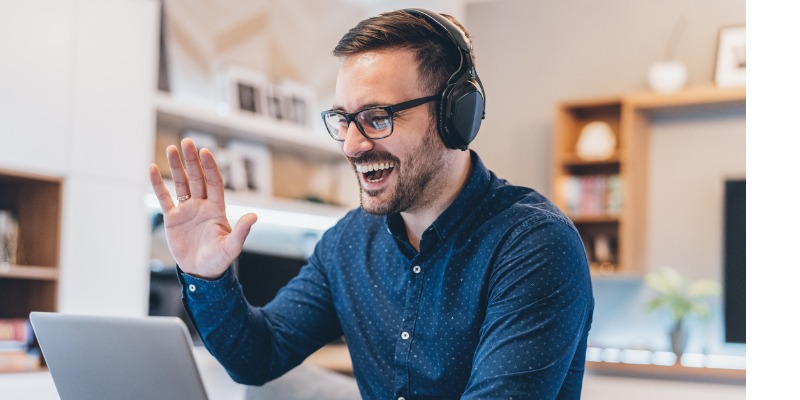 Man on conference call working from home, waving to colleagues 